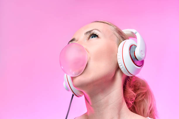 chica rubia infla un chicle en un fondo rosa - blowing hair audio fotografías e imágenes de stock