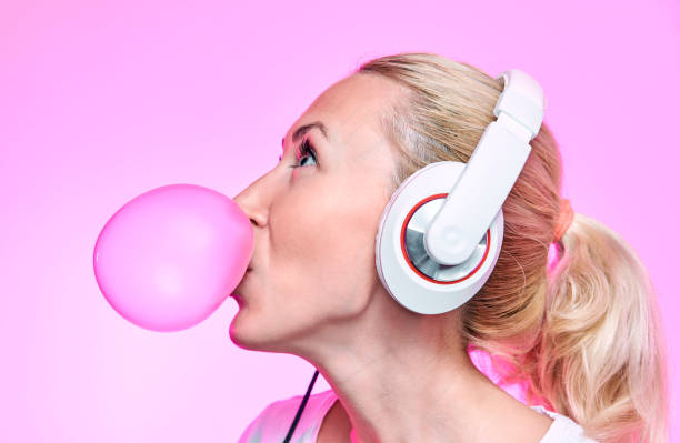 blondynka nadmuchuje gumę bąbelkową na różowym tle - chewing gum audio zdjęcia i obrazy z banku zdjęć