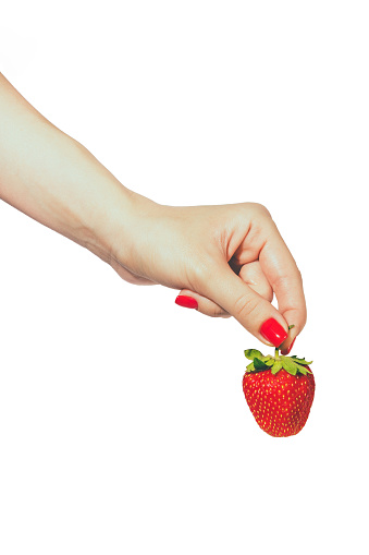 Woman manicured hands whith red nails polish holding fresh strawberries on white background.