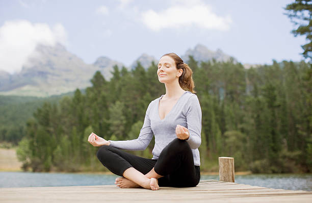 mujer practicar yoga en el muelle junto al lago - exercising female isolated relaxation fotografías e imágenes de stock