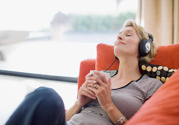 mulher ouvir para auscultadores no sofá - music listening women relaxation imagens e fotografias de stock