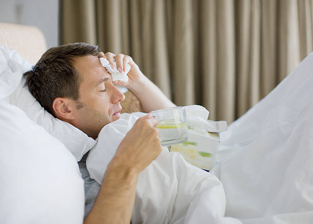 Man sick in bed drinking hot drink  cold and flu man stock pictures, royalty-free photos & images