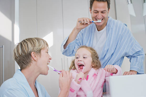 familia cepillar los dientes juntos - human teeth child smiling family fotografías e imágenes de stock