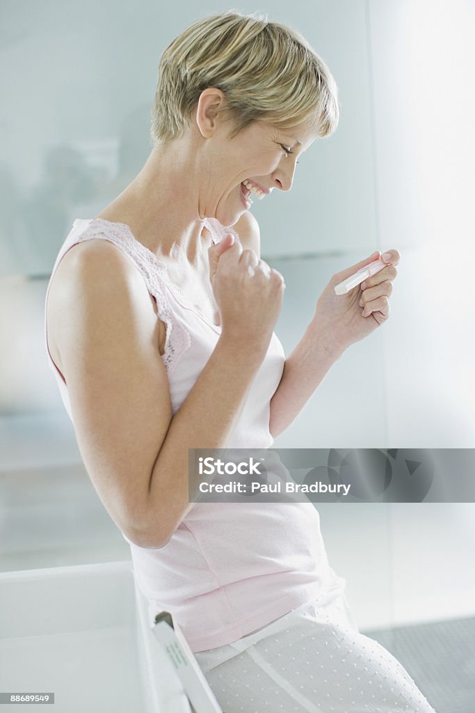 Excited woman looking at pregnancy test  Pregnancy Test Stock Photo