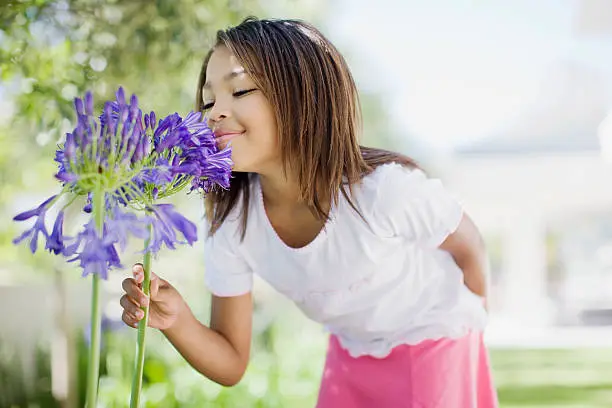 Photo of Young girl smelling flower