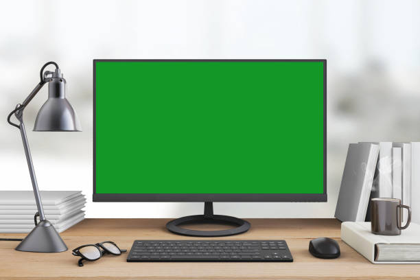Office desk with large PC computer screen with green background - template Interior scene with large PC monitor computer screen of the office desk. Keyboard, mouse, coffee cup, table lamp. Green screen for easier copy space. Business template mock up for designers chroma key photos stock pictures, royalty-free photos & images