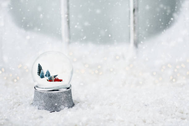 Snow Globe with Toy Truck Silver snow globe with antique toy truck hauling a Christmas tree. Snowglobe is sitting outdoors on the ledge of an old wooden window in the snow. snow globe photos stock pictures, royalty-free photos & images