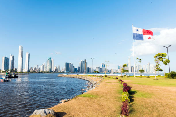 Panama city skyline Panorama Panama city, in front belt of grass at the sea with a Panamanian flag, in background line of skyscrapers and blue sky. Panama panama photos stock pictures, royalty-free photos & images