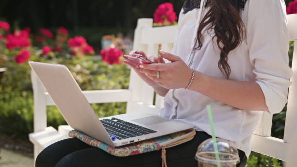 istock Lady Sitting in the Park and Using Laptop and Phone 886930414