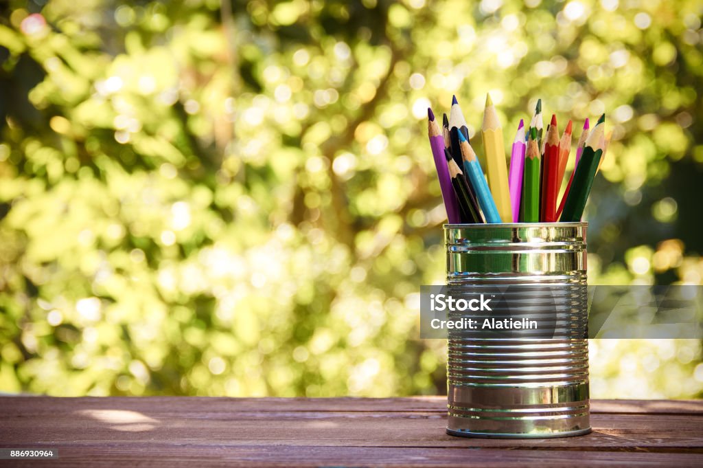 Iron bank with colored pencils on a wooden table. Eco-style. Copy space Can Stock Photo