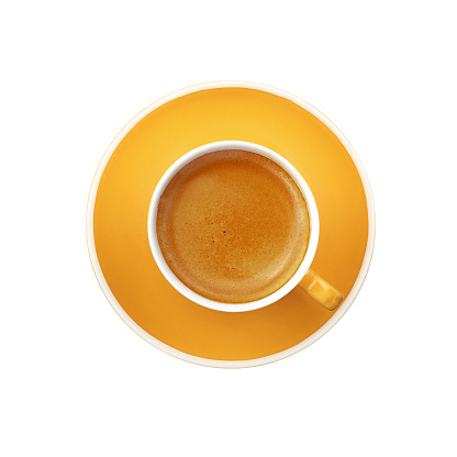 Full espresso in yellow cup with saucer isolated on white on background, elevated top view, close up