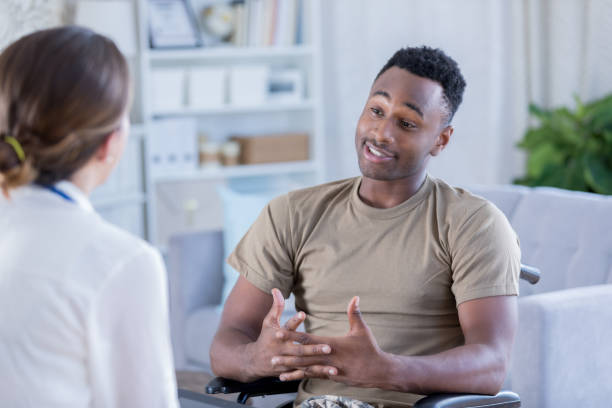 Male soldier discusses issues with therapist African American soldier in a wheelchair discusses problems with a female mental health professional. black military man stock pictures, royalty-free photos & images