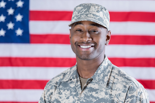 Confident American hero smiles while standing in front of the American flag.