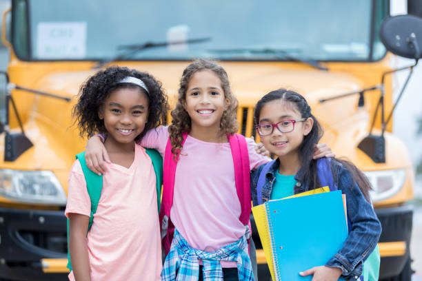 istock Diverse school friends in front of school bus 886933790