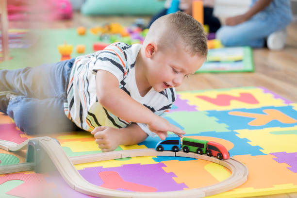 Little boy moves toy train along its track
