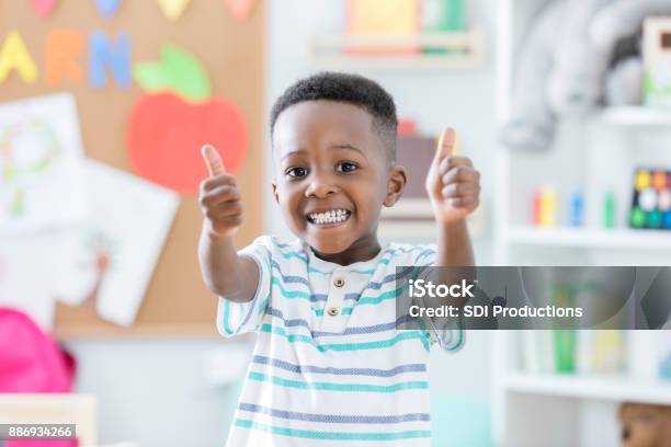 Entzückende Junge Gibt Daumen Nach Oben In Der Vorschule Stockfoto und mehr Bilder von Kind