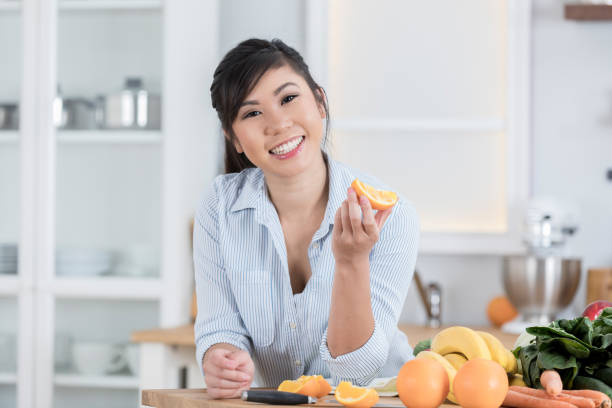 istock Healthy young woman eats an orange slice 886934356