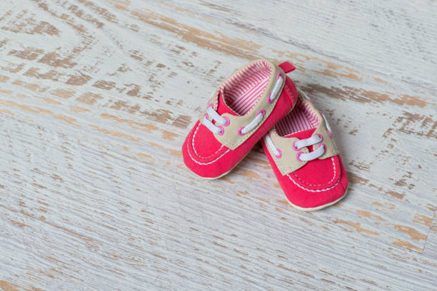 istock Baby red shoes on a rope against a white brick wall 886935358