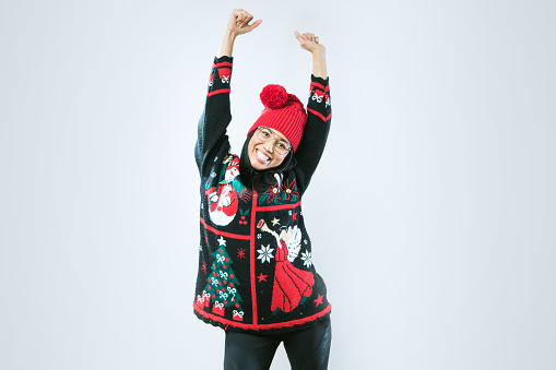 A happy Asian - Pacific Island woman wears an ugly Christmas sweater, having fun during the holiday season.