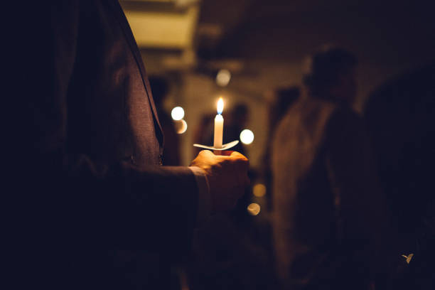 Candlelight Church Service on Christmas Eve A mans hands visible holding a candle during a church celebration on the eve of Christmas day, the final day of advent. religious service photos stock pictures, royalty-free photos & images