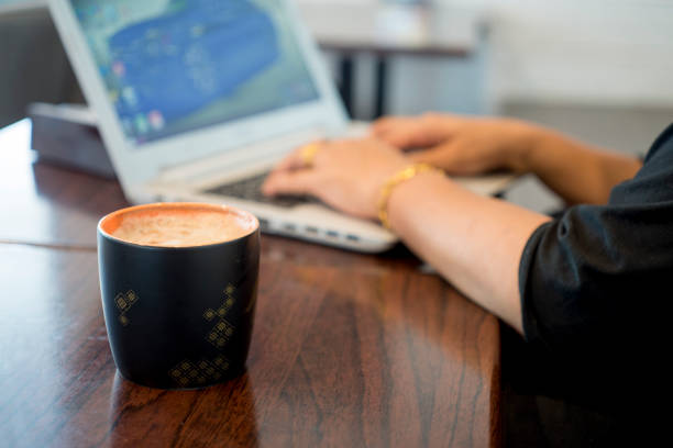 ラップトップ上で入力の女性両手のコーヒー カップ - computer key internet cafe coffee internet ストックフォトと画像