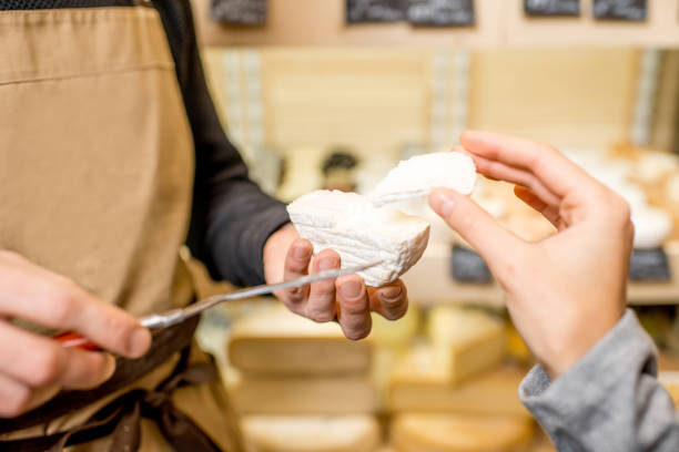 couper un fromage pour le client de la femme - cheese making photos et images de collection