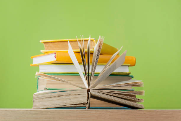 istock Composition with open book, hardback books on wooden table and green background. Back to school..Education background. 886964450