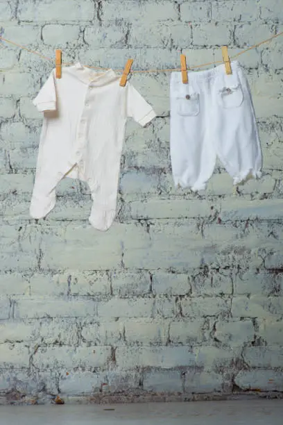 Children's white body and pantyhose dry on a rope against a white brick wall