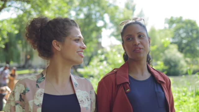 Women friends walking and talking in sunny park