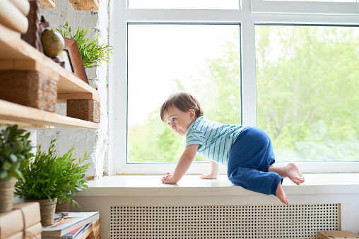 Curious concentrated boy climbing on window sill knowing new place of flat