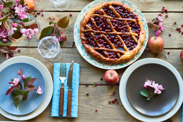 High angle view of appetizing cherry pie and served plates decorated with pink twigs