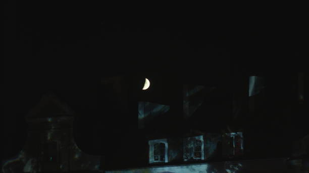 istock Half Moon Shining Over the House Roof at Night 887008912