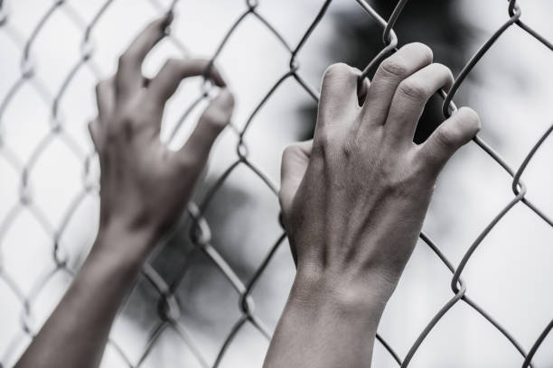 istock Woman hand holding on chain link fence for remember Human Rights Day concept. 887028590