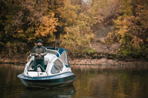 An abstract crop of fishing rods and equipment inside a motorboat as it moves along a river.