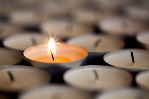 istock Selective focus on magical light from a single sparkling flame from one candle among many extinguished tealight candles. 887034986