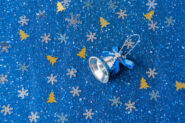 istock Silver bell on a blue background with snowflakes and fir-trees 887088338
