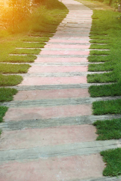 istock Wood-Stone pathway in the park with green grass background. Walkway with sunlight. 887088830