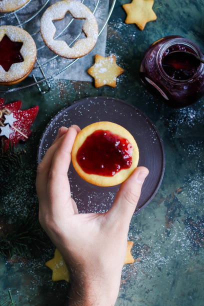 istock Process making of cookies by hand. Christmas Linzer cookies with raspberry jam on green table background. Top view and copy space. Hands cooking 887093686