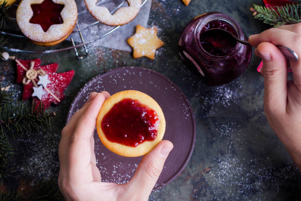 istock Process making of cookies by hand. Christmas Linzer cookies with raspberry jam on green table background. Top view and copy space. Hands cooking 887093698