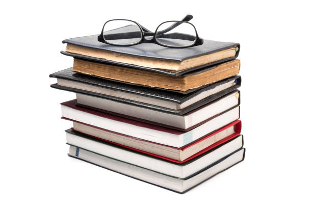 istock A stack of books with eyeglasses on a white background. 887093950
