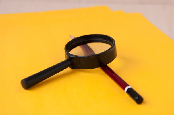 istock Pencil and magnifier on yellow sheets of paper 887103280