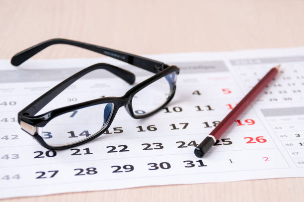 istock Black glasses and a pencil lie on the calendar 887103368