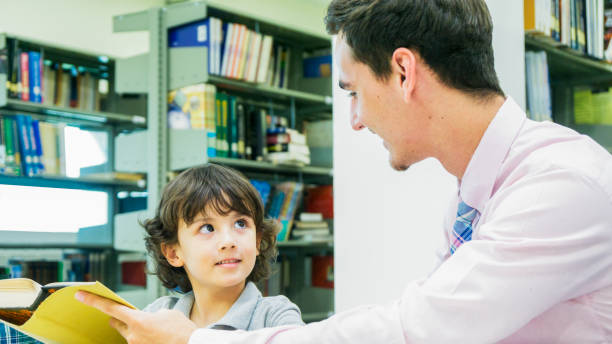 istock teacher and boy student learn with book with bookshelf background 887116024