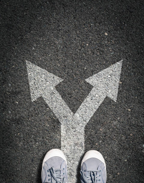 shoes on asphalt road with two directions sign, concept is making choice and makin decsion shoes on asphalt road with two directions sign, concept is making choice and makin decsion pavement ends sign stock pictures, royalty-free photos & images
