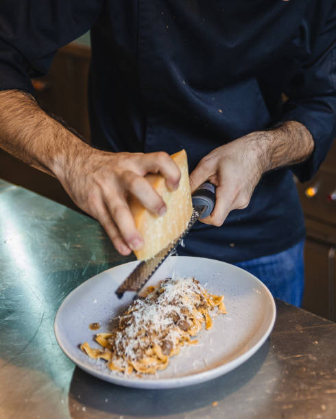 istock Chef scraping fresh cheddar cheese on Wagyu Ragu with Tagliatelle pasta. 887129920