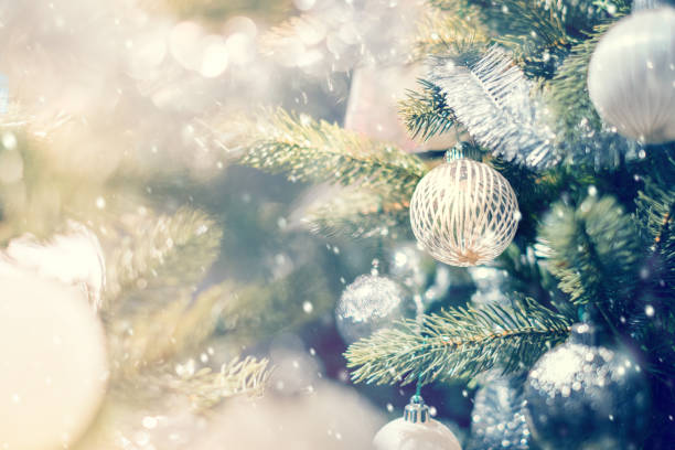 istock White and silver bauble hanging from a decorated Christmas tree with background. 887161256