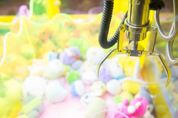 istock Claw Game or cabinet catches the doll.A mechanical arm selecting a random soft toy in a vending machine 887167002