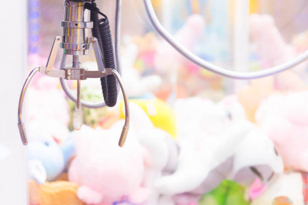istock Claw Game or cabinet catches the doll.A mechanical arm selecting a random soft toy in a vending machine 887167016