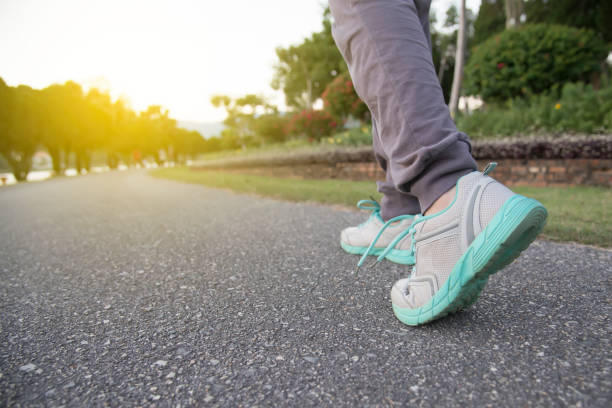 女性スニーカー夕方ジョギングで足がマラソンの準備を実行して、健康的なライフ スタイル スポーツ女性スポーツの靴、道路で実行されている、成功への道 - 歩く ストックフォトと画像