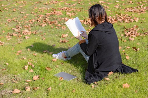woman reading book on lawn in weekend.